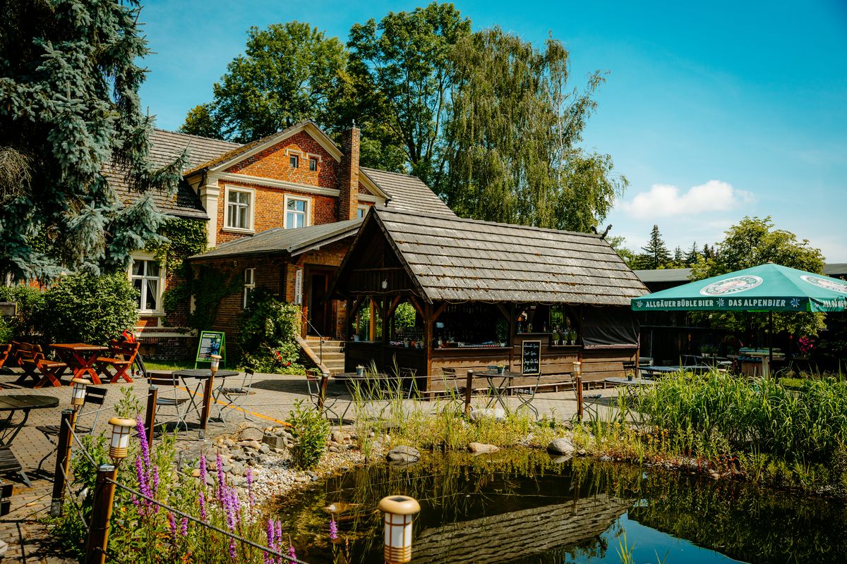 Kolonieschänke: Holzhaus mit Teich im Hof